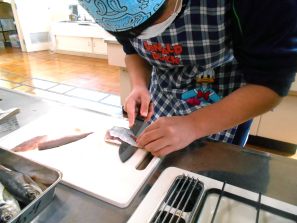 包丁で魚を下ろす子供